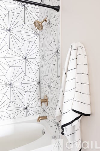 A white towel hangs on a shower rod in a bathroom.