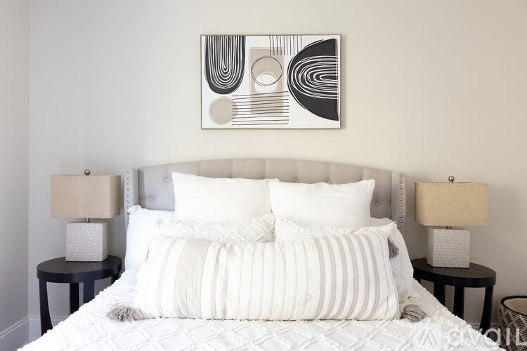 A bed with a white comforter and two pillows sits in a room with two lamps on side tables.