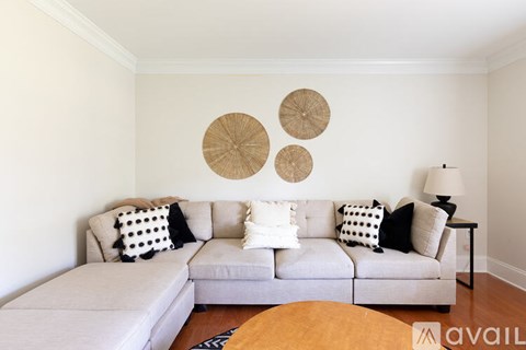 A living room with a grey couch and three decorative plates on the wall.