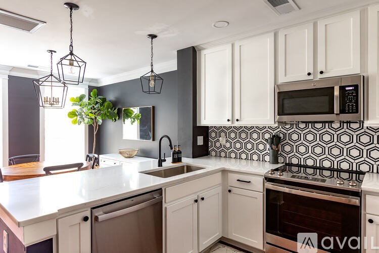 A kitchen with a white counter top and a black and white tiled backsplash.