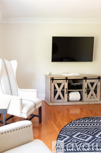 A white chair sits in front of a tv on a wooden stand.