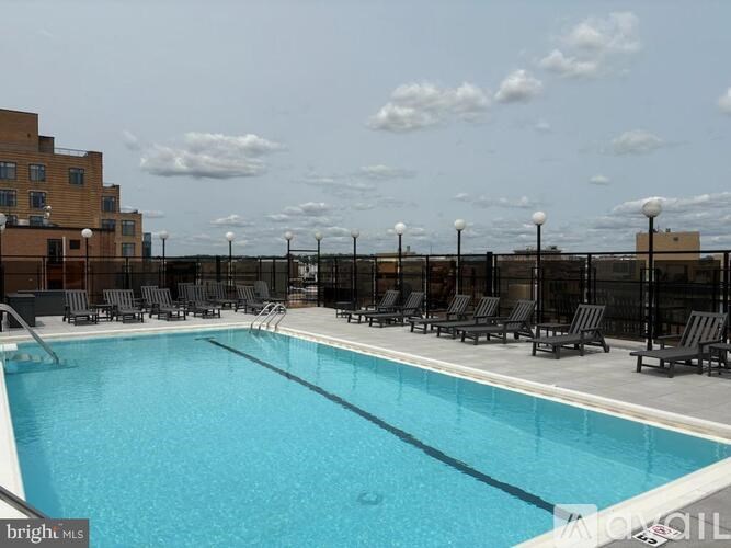 A large outdoor swimming pool surrounded by black lounge chairs.