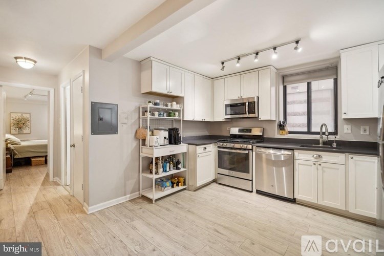 A well-lit kitchen with white cabinets and stainless steel appliances.