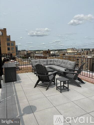A balcony with a couch, chairs and a table with a view of the city.