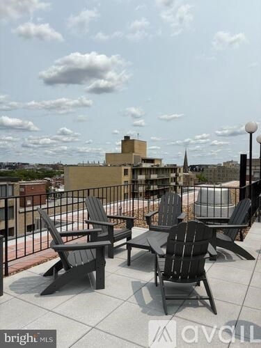 A balcony with chairs and a table is overlooking a cityscape.