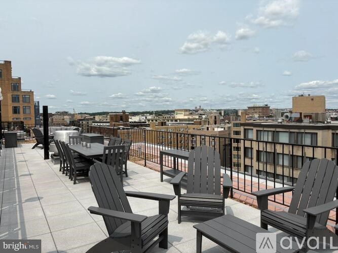 A balcony with black furniture overlooking a cityscape.