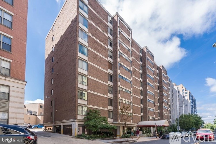 A tall brick building with a parking lot in front.