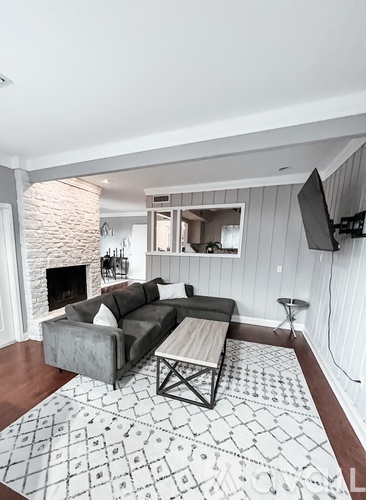 A living room with a grey couch and a patterned rug.