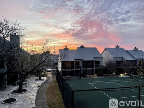 A tennis court is surrounded by houses and trees.