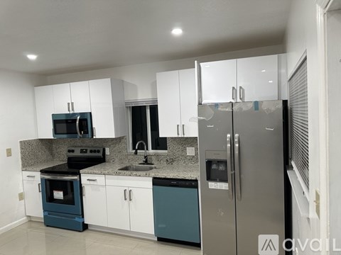 A kitchen with white cabinets and a stainless steel refrigerator.