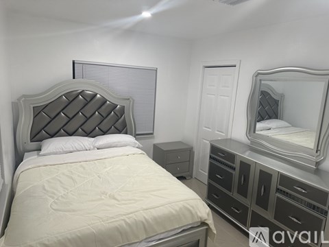A bedroom with a large bed, a vanity with a mirror, and a nightstand.