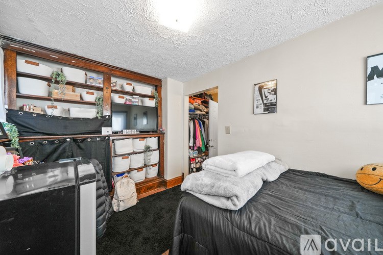 A bedroom with a bed, a washing machine, and a wall-mounted shelf with various items.