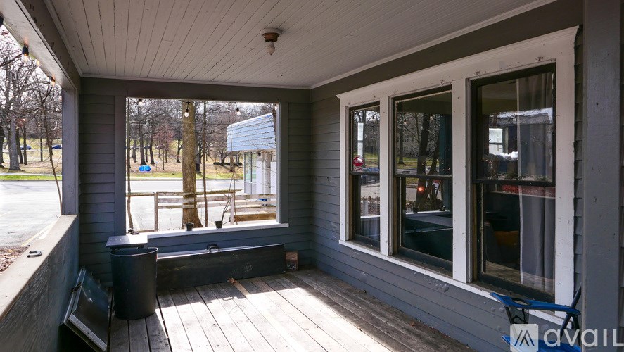 A porch with a bench and a window overlooking a yard.