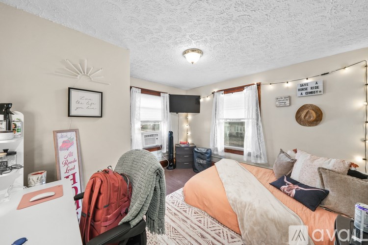 A bedroom with a bed, a fridge, and a sign that says "Welcome to the newest member of the family".