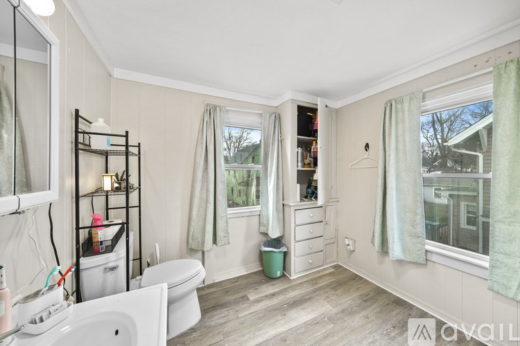 A bathroom with a white toilet, sink, and a window with a view of trees.