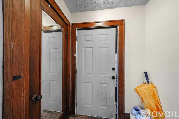 A room with a white door, a brown door and a yellow umbrella.