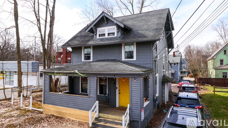 A grey house with a yellow door is surrounded by other houses.