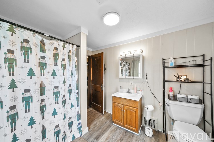 A bathroom with a shower curtain featuring Christmas trees and presents.