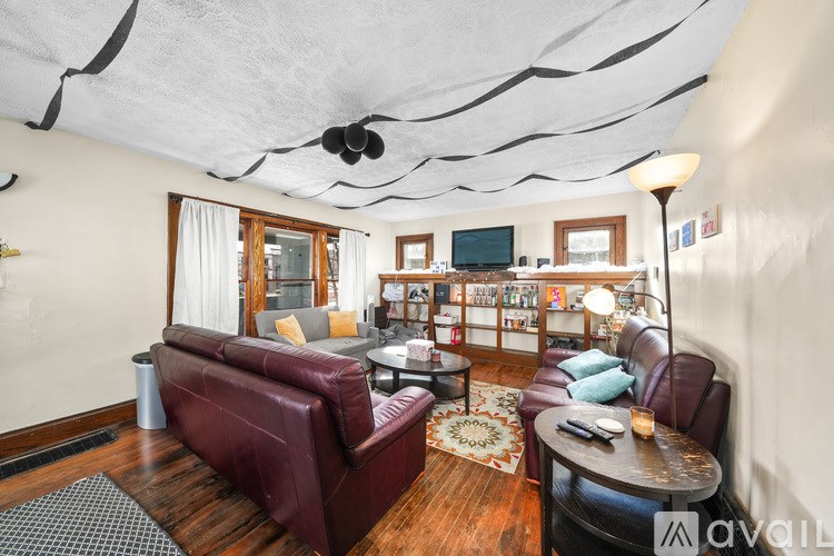 A living room with a red couch and a wooden floor.