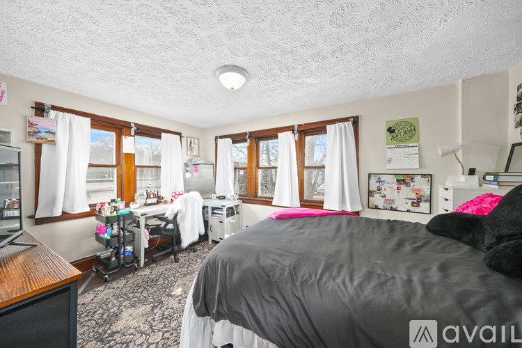 A bedroom with a bed, a chair, and a table with a lamp.