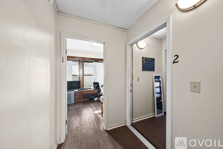 A hallway with a mirror on the wall and a door leading to a living room.