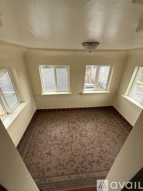 A room with a brick floor and three windows.