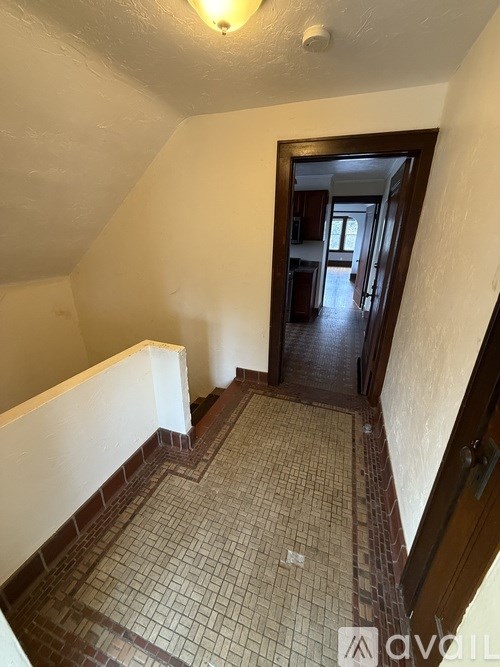 A hallway with a tiled floor and a doorway leading to another room.