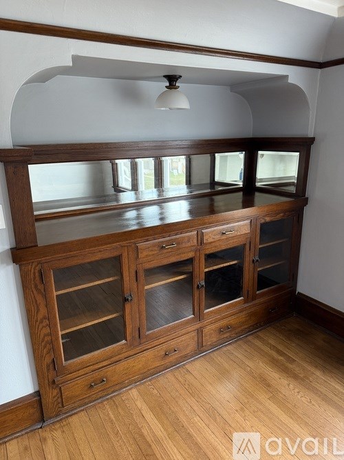 A wooden cabinet with glass doors is in the foreground.