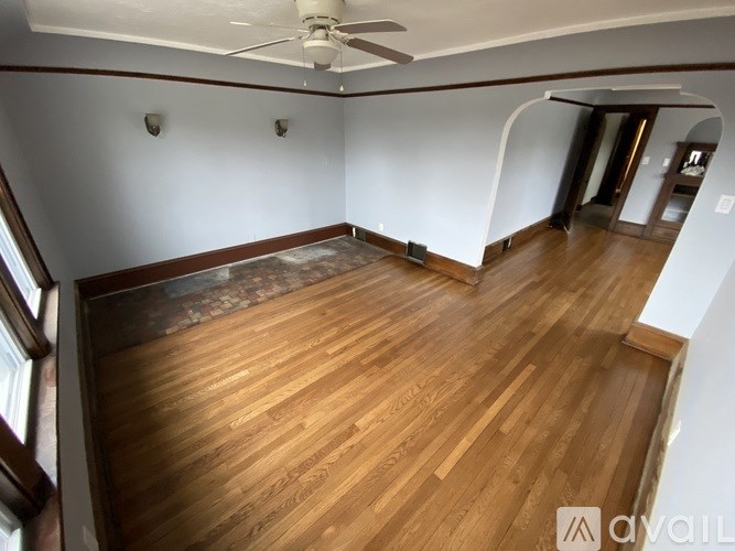 A room with wooden flooring and a ceiling fan.