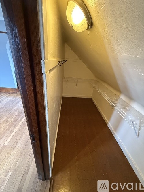 A hallway with a light on the wall and a wooden floor.