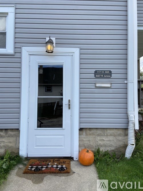 A blue door with a sign above it and a pumpkin on the mat.