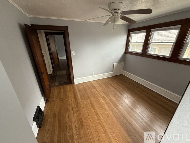 A room with a ceiling fan and wooden flooring.