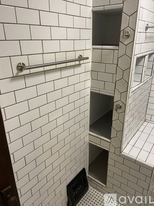 A white tiled bathroom with a towel bar and shelves.