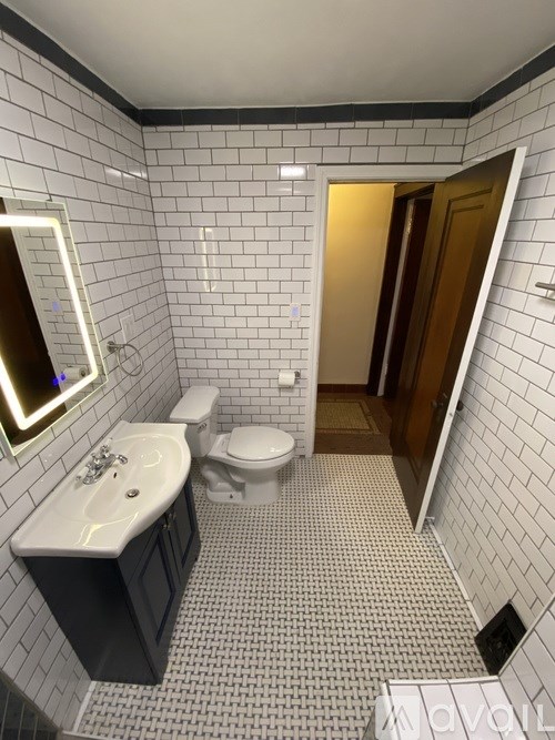 A bathroom with a toilet, sink, and mirror.