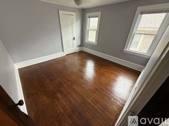 A room with wooden floors and two windows.