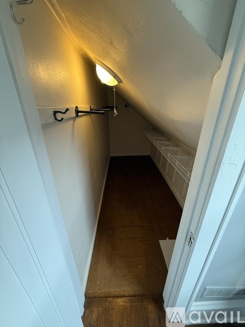 A narrow hallway with a light on the ceiling and a staircase on the right.