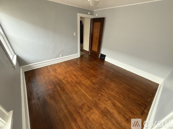 A room with wooden flooring and a staircase on the left side.