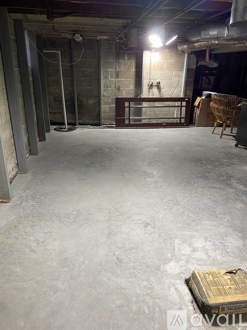 A large, empty room with concrete floors and walls, and a few pieces of furniture.