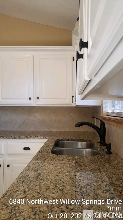 A kitchen with granite countertops and white cabinets.