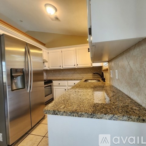 A kitchen with white cabinets and a granite countertop.