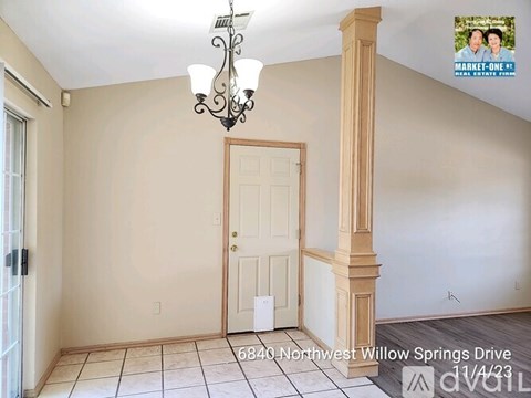 A room with a door and a chandelier hanging from the ceiling.