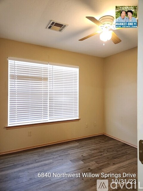 A room with a ceiling fan and a window with blinds.