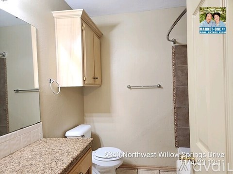 A bathroom with a toilet, sink, and a poster on the wall.