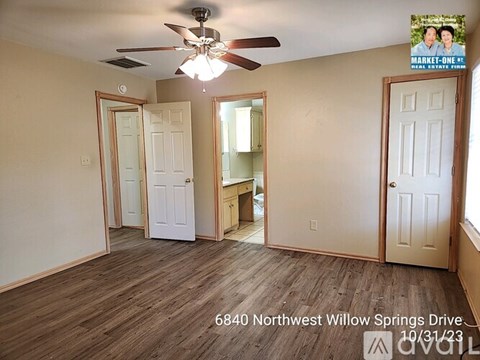 A room with a ceiling fan and a sign that says Market One Real Estate.