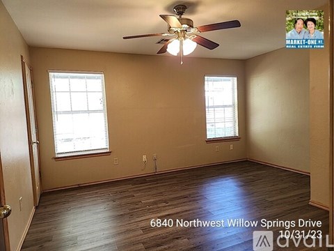 A room with a ceiling fan and two windows.