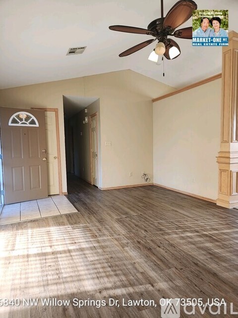 A room with a ceiling fan and a door leading to another room.