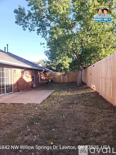 A backyard with a tree and a fence.