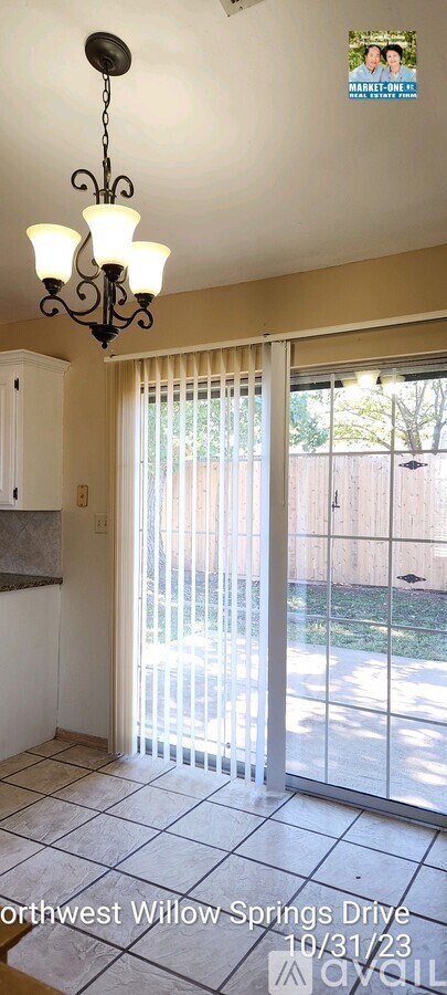 A room with a chandelier and sliding glass doors leading to a backyard.