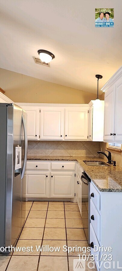 A kitchen with white cabinets and a granite countertop.