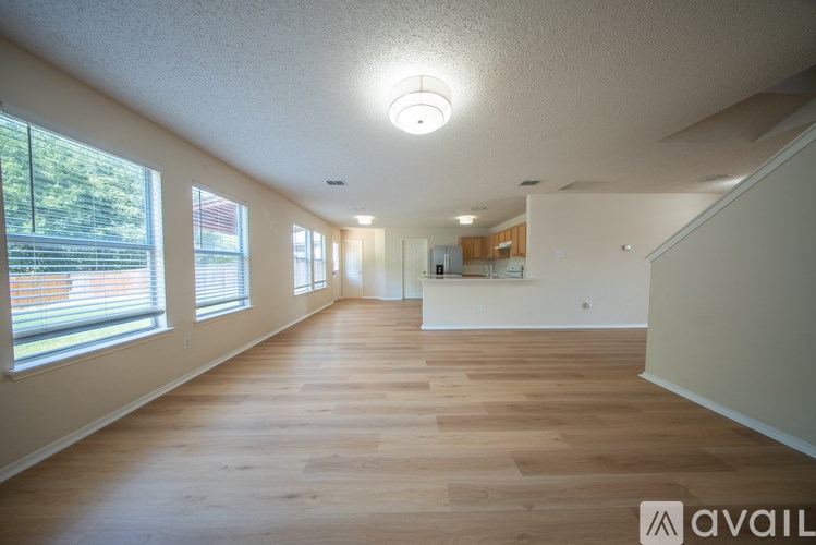 A spacious room with wooden floors and a large window on the left side.